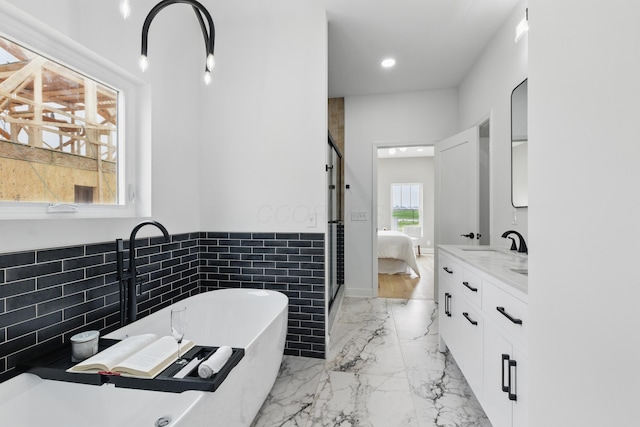 bathroom with vanity, marble tiled flooring, ensuite bath, a freestanding tub, and a wainscoted wall