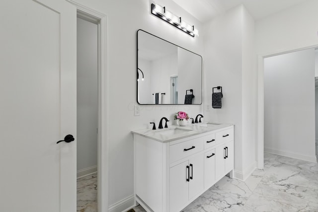 full bath featuring marble finish flooring, baseboards, and double vanity