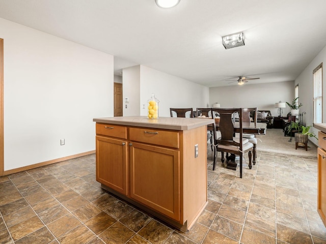 5292 Winters Run Rd, Dublin, OH 43016 - kitchen with ceiling fan, stone finish floors, a kitchen island, light countertops, and baseboards