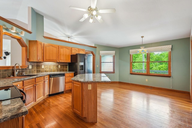 4217 Caswell Rd, Johnstown, OH 43031 - kitchen with stainless steel appliances, a sink, a kitchen island, light wood-type flooring, and decorative backsplash