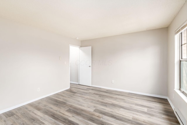 spare room with light wood-style floors and baseboards