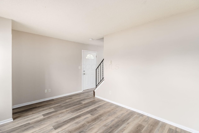 foyer entrance featuring wood finished floors, baseboards, and stairway