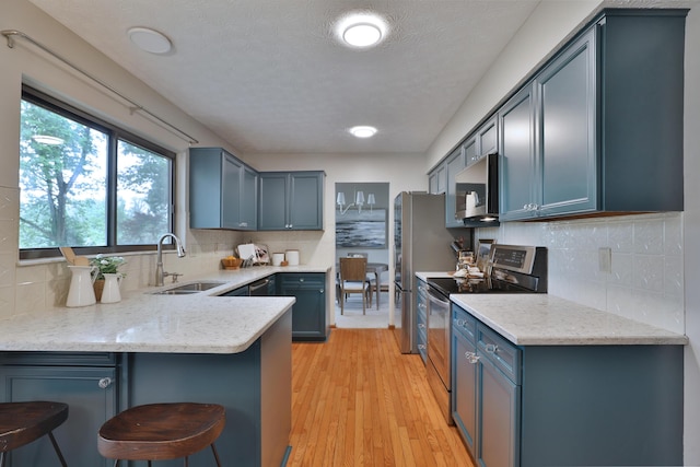 587 Center Woods Dr, Columbus, OH 43214 - kitchen with appliances with stainless steel finishes, a sink, a peninsula, blue cabinets, and a breakfast bar