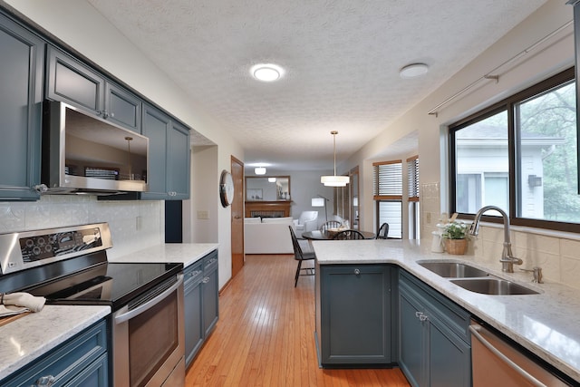 587 Center Woods Dr, Columbus, OH 43214 - kitchen with stainless steel appliances, a sink, decorative backsplash, a textured ceiling, and a peninsula