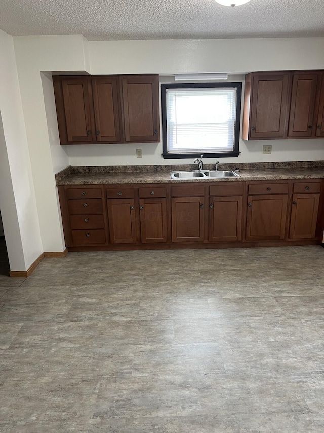 65 E N St, Newark, OH 43055 - kitchen with a sink, dark countertops, a textured ceiling, light wood finished floors, and baseboards