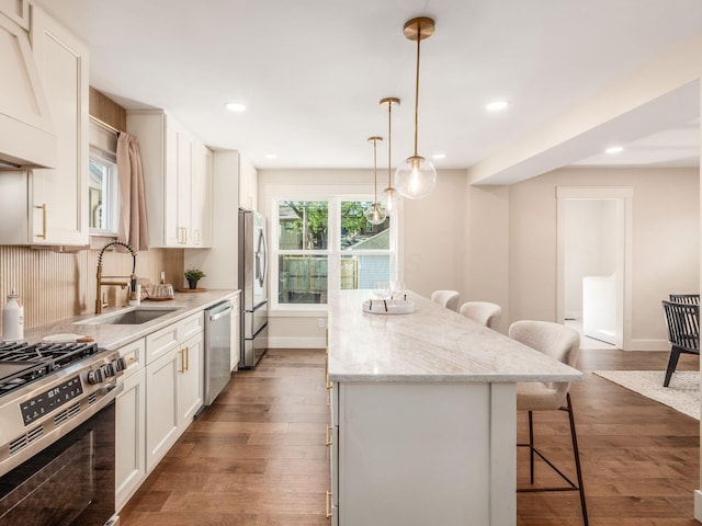 697 Stanley Ave, Columbus, OH 43206 - kitchen featuring a sink, appliances with stainless steel finishes, a kitchen breakfast bar, a kitchen island, and dark wood-style floors