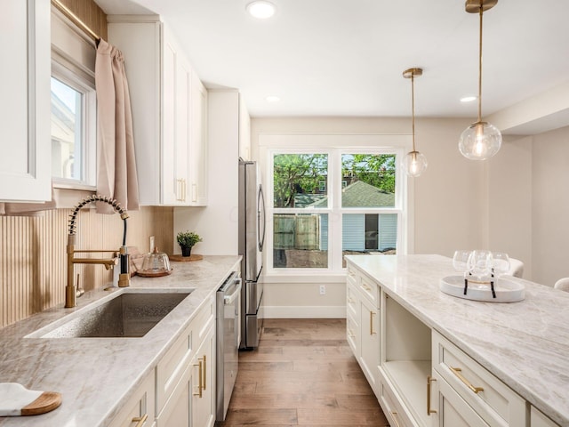 697 Stanley Ave, Columbus, OH 43206 - kitchen with a sink, appliances with stainless steel finishes, light wood-style floors, hanging light fixtures, and white cabinets