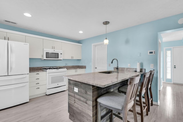kitchen featuring white appliances, a sink, a peninsula, light wood-style flooring, and white cabinetry