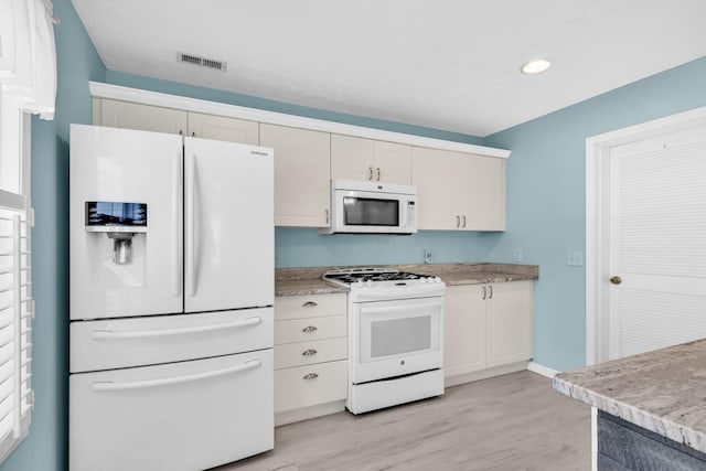 kitchen featuring white appliances, light wood-style flooring, light countertops, recessed lighting, and white cabinetry