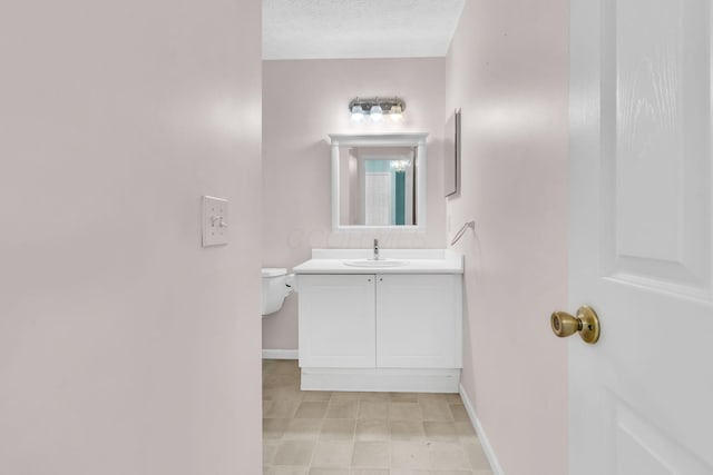 half bath with vanity, baseboards, and a textured ceiling