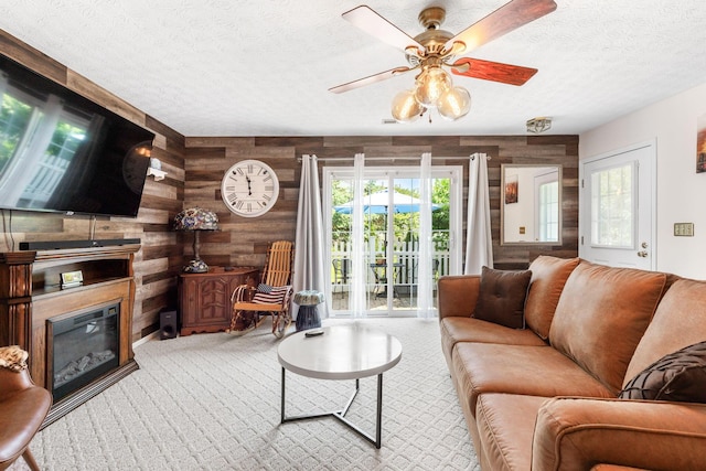 4642 Hobson Dr Unit 13E, Columbus, OH 43228 - living room featuring wood walls, a textured ceiling, carpet floors, a ceiling fan, and a glass covered fireplace