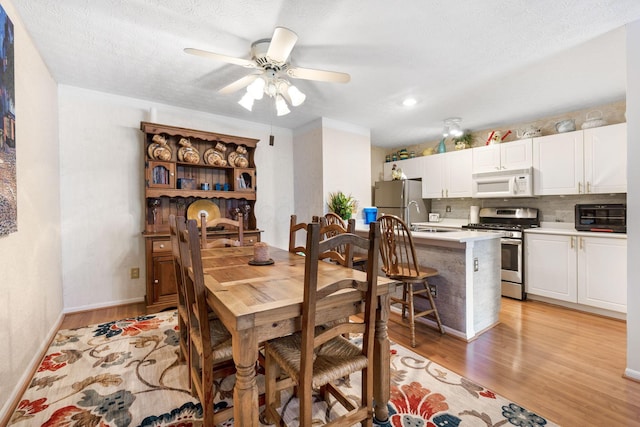 4642 Hobson Dr Unit 13E, Columbus, OH 43228 - dining room featuring light wood-type flooring, ceiling fan, baseboards, and a textured ceiling