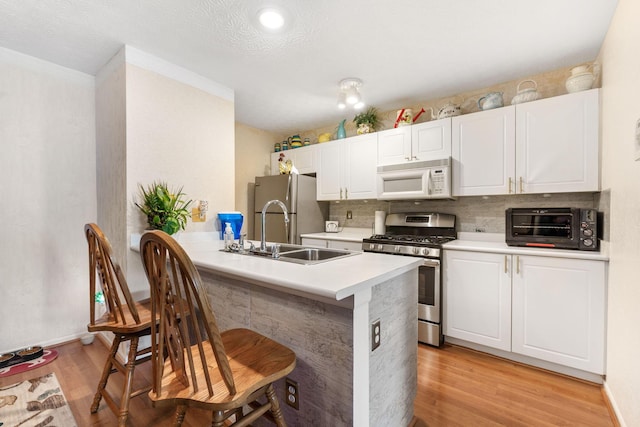 4642 Hobson Dr Unit 13E, Columbus, OH 43228 - kitchen featuring stainless steel appliances, a sink, a kitchen bar, light wood finished floors, and light countertops
