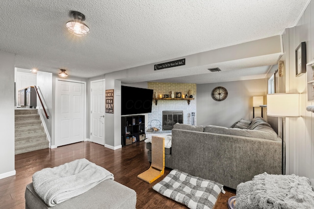 2923 Falcon Bridge Dr, Columbus, OH 43232 - living area featuring a textured ceiling, wood finished floors, a brick fireplace, stairway, and baseboards