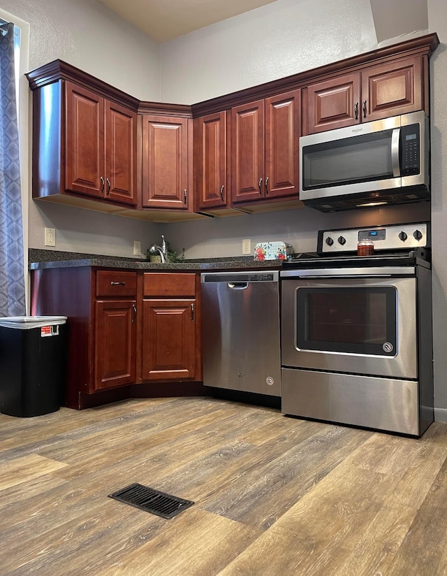 130 N 4th St, Greenfield, OH 45123 - kitchen with stainless steel appliances, light wood-type flooring, dark countertops, a textured wall, and a sink