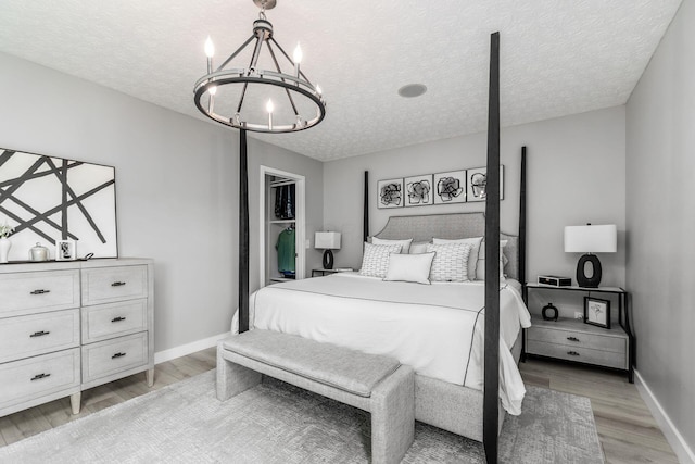 7834 Avaleen Cir N, Dublin, OH 43016 - bedroom with a chandelier, light wood finished floors, a textured ceiling, and baseboards