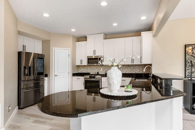 7834 Avaleen Cir N, Dublin, OH 43016 - kitchen featuring appliances with stainless steel finishes, a peninsula, a sink, backsplash, and light wood-type flooring