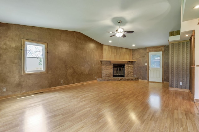unfurnished living room with a ceiling fan, light wood finished floors, a brick fireplace, lofted ceiling, and baseboards