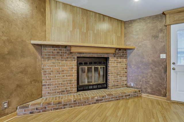 detailed view of wood finished floors, a fireplace, and baseboards