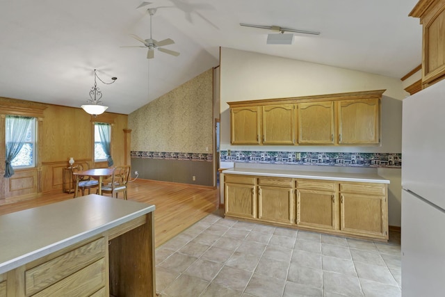 kitchen with freestanding refrigerator, ceiling fan, a wainscoted wall, vaulted ceiling, and light countertops