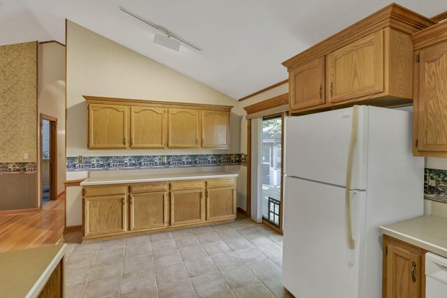 kitchen with white appliances, vaulted ceiling, light countertops, and brown cabinetry