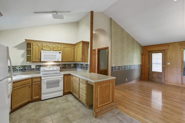 kitchen featuring white appliances, a peninsula, a sink, light countertops, and high vaulted ceiling