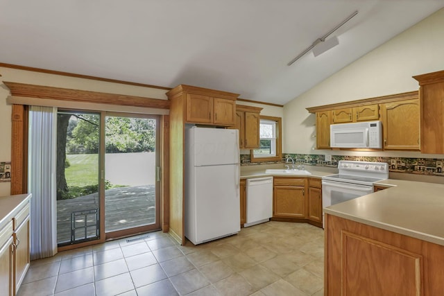 kitchen with white appliances, a sink, vaulted ceiling, light countertops, and brown cabinetry