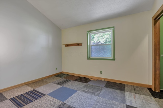 carpeted empty room featuring baseboards and lofted ceiling