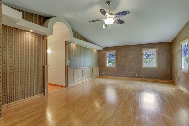 unfurnished room featuring a ceiling fan, wood finished floors, vaulted ceiling, baseboards, and arched walkways