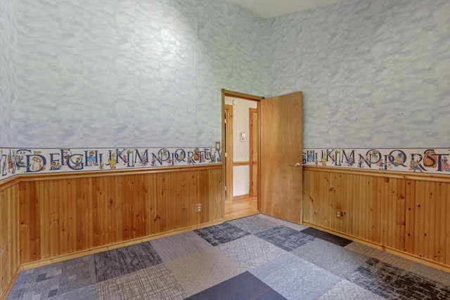 empty room featuring wainscoting and wood walls