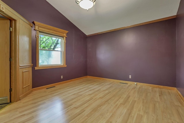 spare room featuring vaulted ceiling, wood finished floors, and baseboards