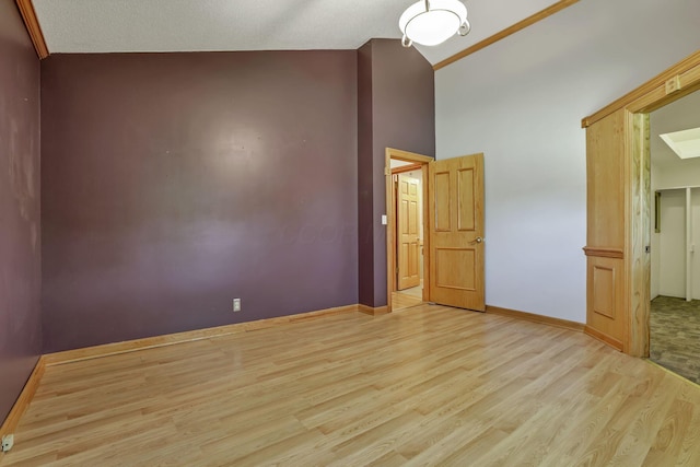 unfurnished bedroom featuring light wood finished floors, baseboards, and high vaulted ceiling