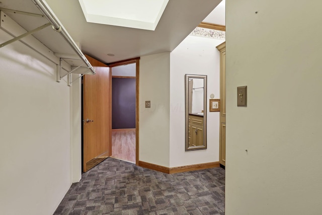corridor featuring dark colored carpet and a skylight