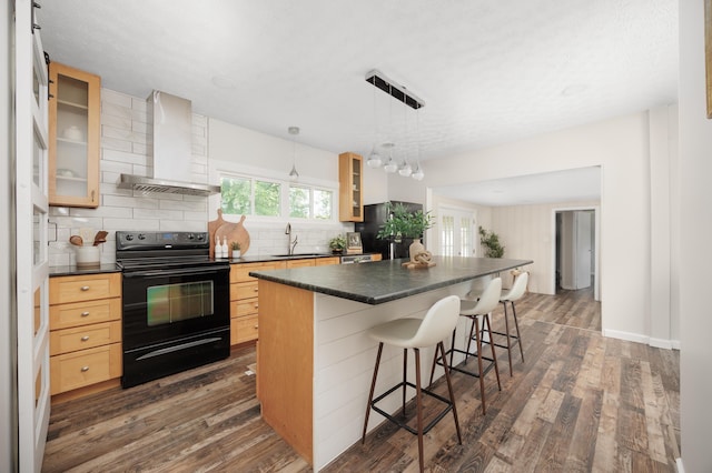 1366 Dyer Rd, Grove City, OH 43123 - kitchen featuring black appliances, wall chimney range hood, dark countertops, dark wood-style floors, and a kitchen breakfast bar