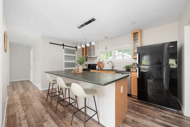 1366 Dyer Rd, Grove City, OH 43123 - kitchen with black appliances, a barn door, dark countertops, wall chimney exhaust hood, and a breakfast bar