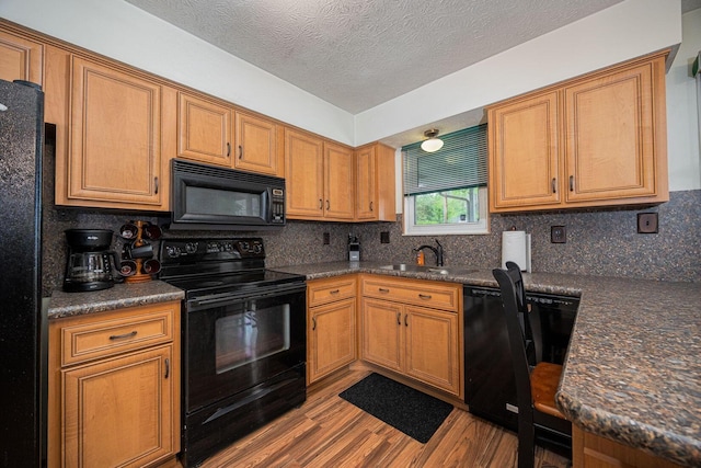 5965 Lucky Charm Dr, Galloway, OH 43119 - kitchen featuring black appliances, a sink, dark countertops, wood finished floors, and tasteful backsplash