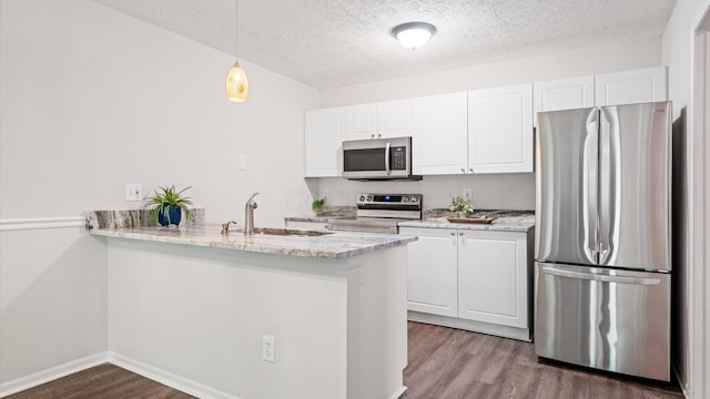 6706 Axtel Dr Unit 7A, Canal Winchester, OH 43110 - kitchen featuring appliances with stainless steel finishes, a sink, wood finished floors, a peninsula, and white cabinetry