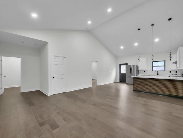 1292 Moundview Ave, Columbus, OH 43207 - unfurnished living room with dark wood-type flooring, baseboards, high vaulted ceiling, and recessed lighting