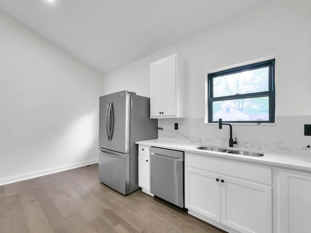 1292 Moundview Ave, Columbus, OH 43207 - kitchen with stainless steel appliances, a sink, light wood-style flooring, white cabinets, and vaulted ceiling