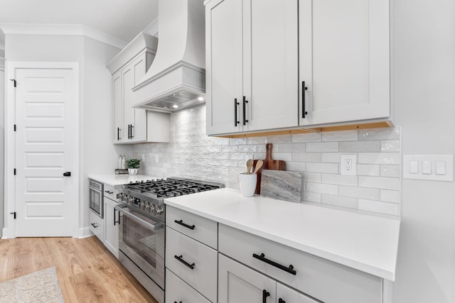 5599 Piatt Rd, Lewis Center, OH 43035 - kitchen with stainless steel range, premium range hood, light wood-style flooring, light countertops, and decorative backsplash
