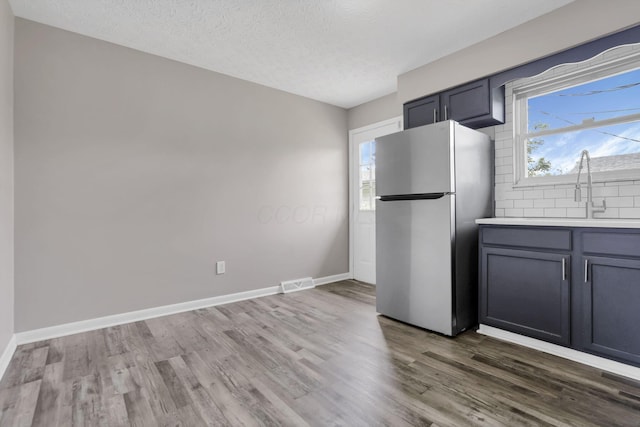 3197 E Ave, Columbus, OH 43207 - kitchen with freestanding refrigerator, a sink, wood finished floors, decorative backsplash, and healthy amount of natural light