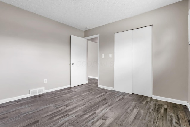 3197 E Ave, Columbus, OH 43207 - unfurnished bedroom featuring wood finished floors, a closet, baseboards, and a textured ceiling