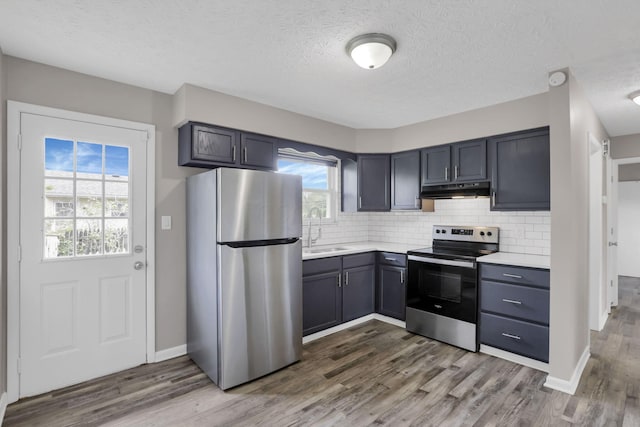 3197 E Ave, Columbus, OH 43207 - kitchen featuring stainless steel appliances, a sink, dark wood-style floors, light countertops, and backsplash