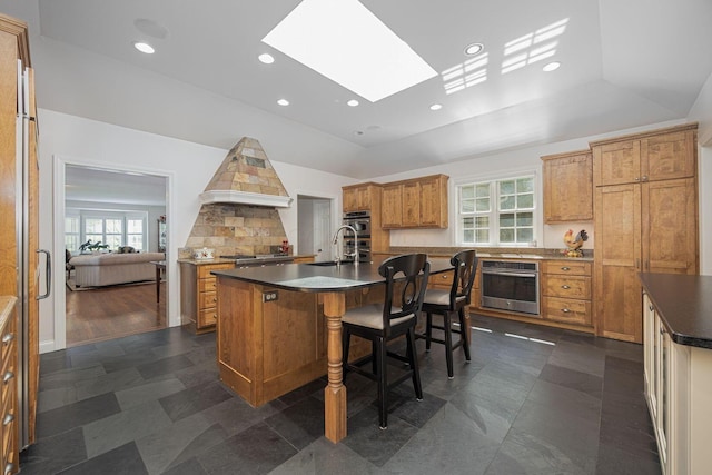 366 W S St, Worthington, OH 43085 - kitchen with a center island with sink, healthy amount of natural light, brown cabinetry, a skylight, and recessed lighting