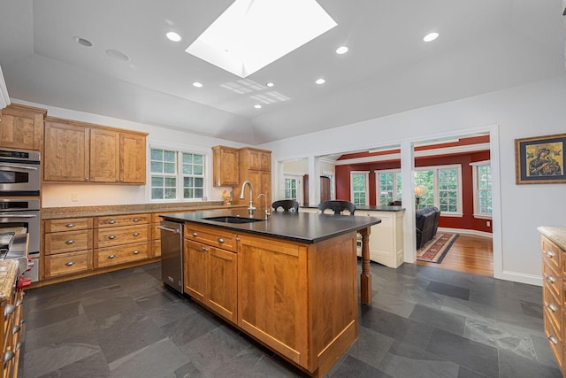 366 W S St, Worthington, OH 43085 - kitchen with a skylight, stainless steel appliances, brown cabinets, a kitchen bar, and a kitchen island with sink