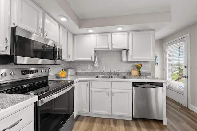 1244 E Choctaw Dr, London, OH 43140 - kitchen with stainless steel appliances, a sink, white cabinetry, light wood finished floors, and tasteful backsplash