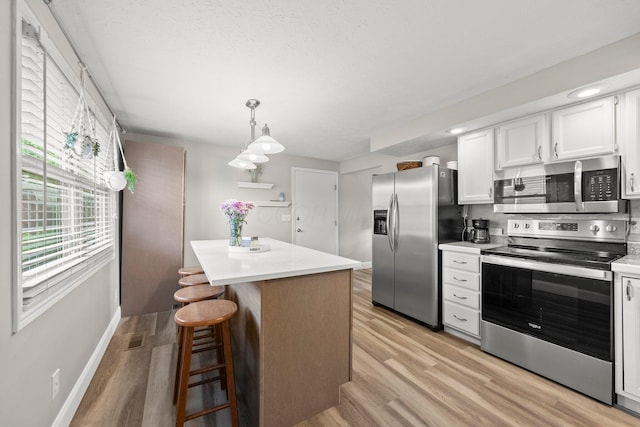 1244 E Choctaw Dr, London, OH 43140 - kitchen featuring stainless steel appliances, light wood finished floors, a center island, light countertops, and a textured ceiling