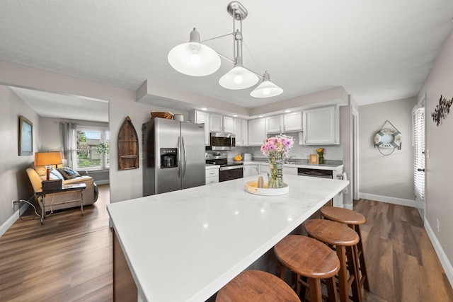 1244 E Choctaw Dr, London, OH 43140 - kitchen with appliances with stainless steel finishes, baseboards, dark wood-style floors, a breakfast bar area, and backsplash