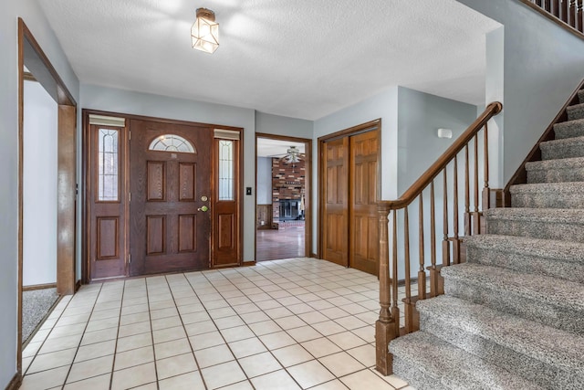 1541 Kensington Ln, Lancaster, OH 43130 - entrance foyer featuring stairs, a textured ceiling, a fireplace, light tile patterned flooring, and baseboards