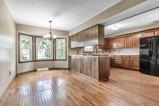 1541 Kensington Ln, Lancaster, OH 43130 - kitchen with freestanding refrigerator, light countertops, a chandelier, light wood finished floors, and plenty of natural light
